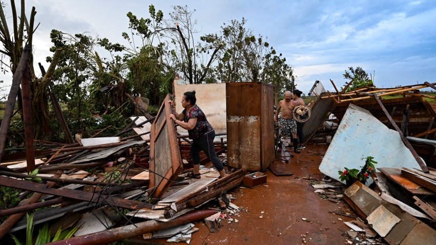 People collect belongings among the debris of a house after the passage of hurricane Rafael in Alquizar, Artemisa province, Cuba on November 7, 2024. Power was restored to parts of Cuba on Thursday a day after Hurricane Rafael swept over the island, leaving its 10 million inhabitants without electricity for the second time in a month. (Photo by Yamil LAGE / AFP) (Photo by YAMIL LAGE/AFP via Getty Images)